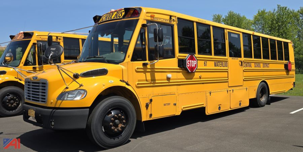 Yellow Freightliner Thomas bus in a parking lot, front-quarter view with Stop sign and school bus markings visible.