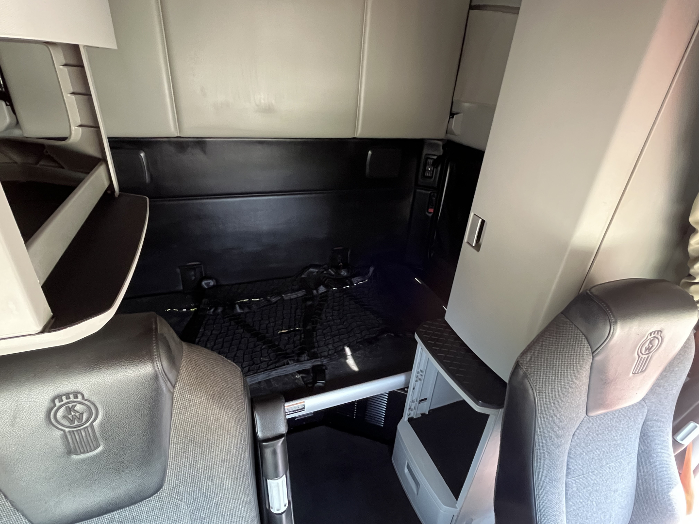 Kenworth T680 cab interior showing sleeper area and dash along with seating and storage compartments.