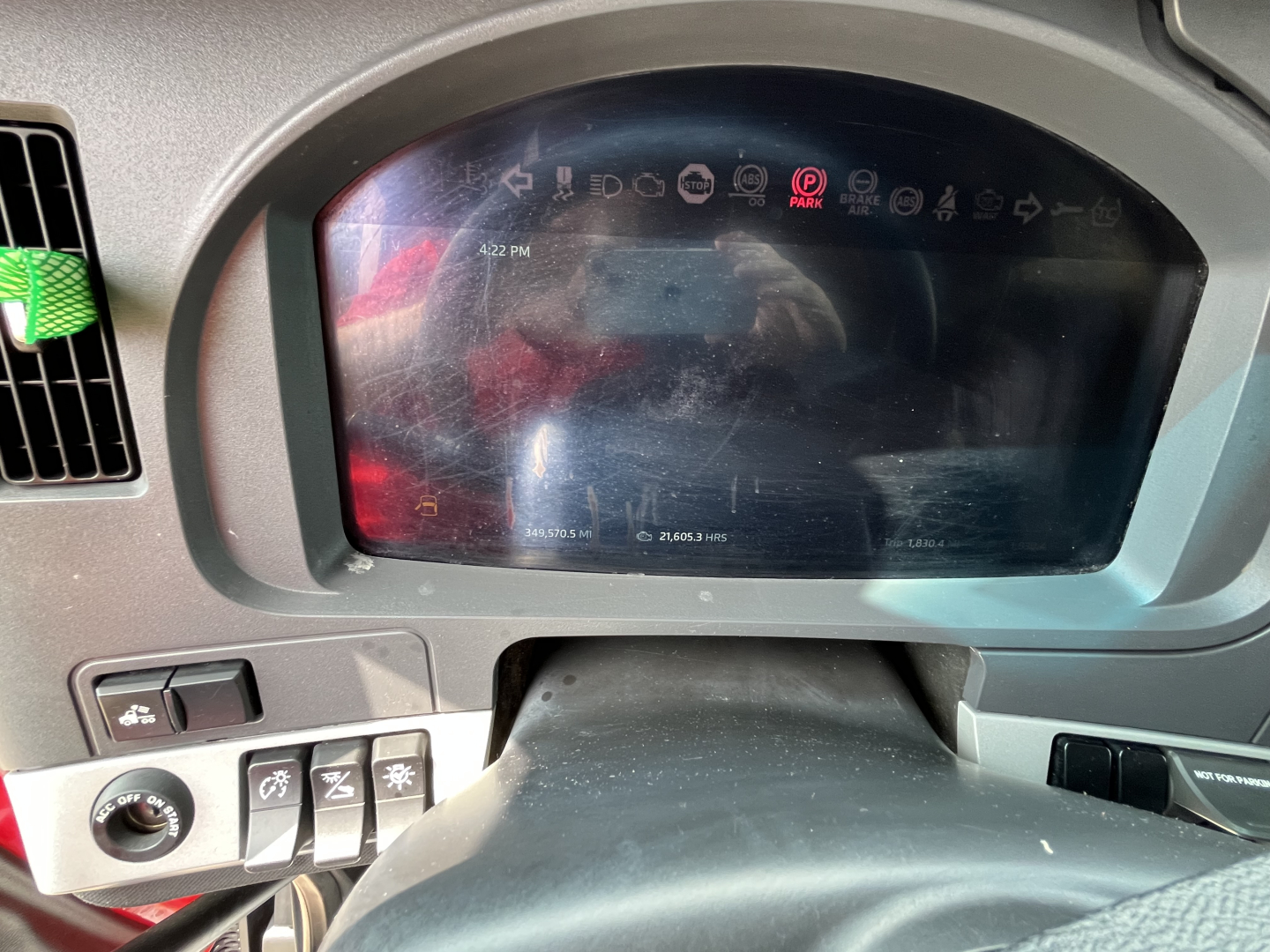 Kenworth T680 dashboard/driver display showing digital instrument cluster and steering column; various controls on left; reflection in screen