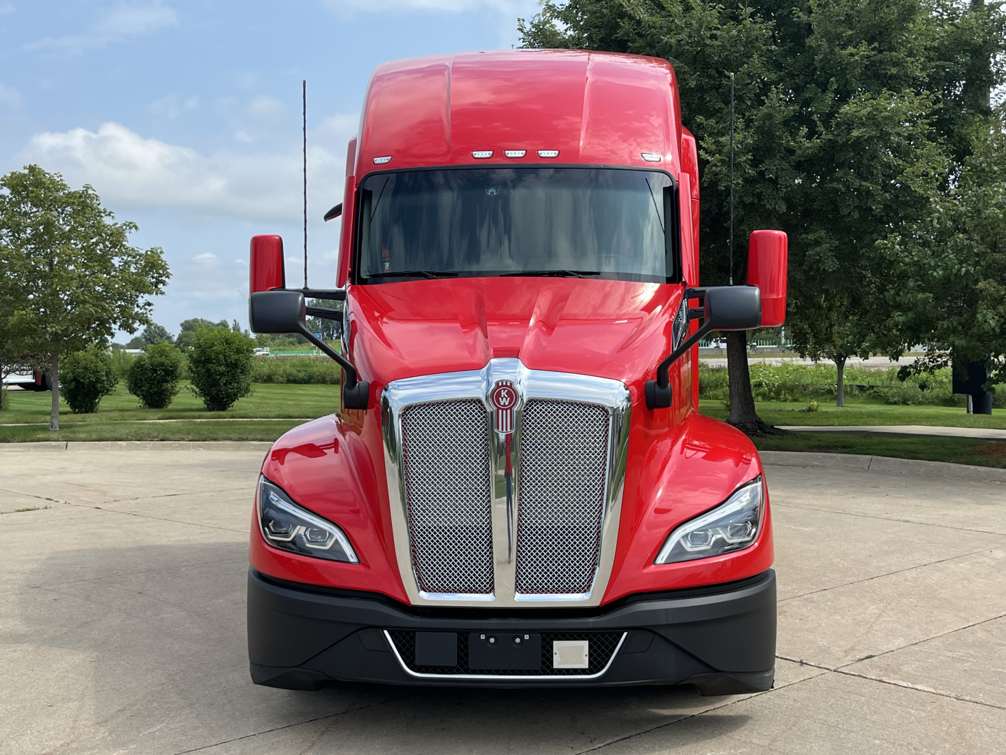 Kenworth T680 truck with red cab from front view showing grille, headlights, and mirrors.