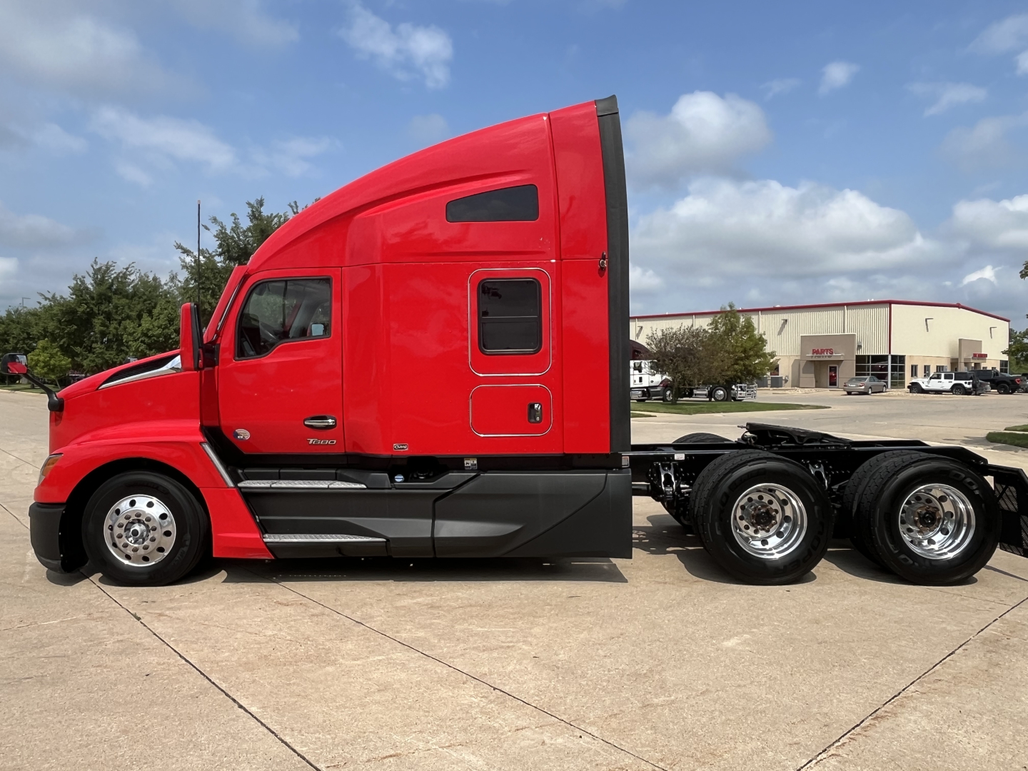 Kenworth T680 truck side profile in red, sleeper cab, with multiple rear axles and chrome wheels visible.