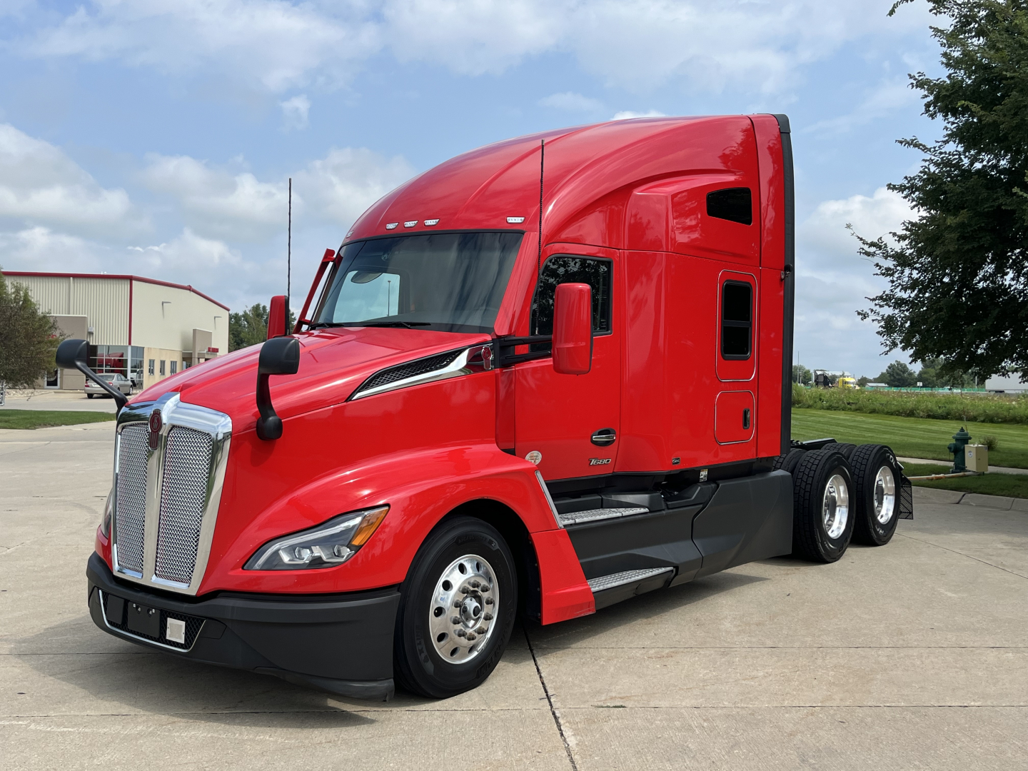 Kenworth T680 tractor in red, front left view, with cab and sleeper. No visible labels readable on image aside from generic truck design.