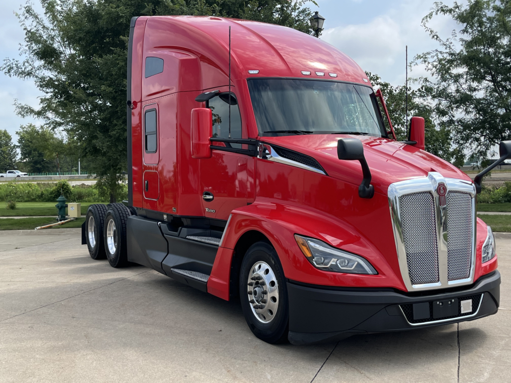 Kenworth T680 truck in red, side view showing aerodynamic cab, chrome grille, dual rear axles, and window mirrors.