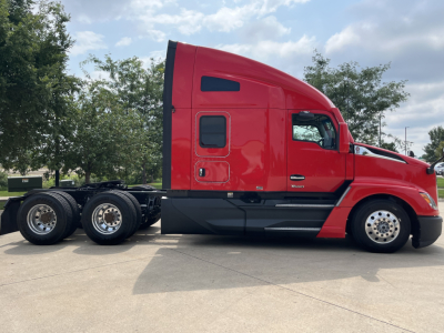 Kenworth T680 daytime side view, red sleeper cab, black lower fairing, triple rear axles, visible wheels, stock number 0629699, VIN 1XKYD49X4RJ344358.
