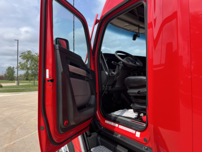 Kenworth T680 truck cab interior with open door showing steering wheel and driver's seat.