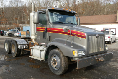 2004 International 9400 daycab truck side view showing cab with vertical exhaust, chrome grille, dual rear axles, and maroon gold stripe