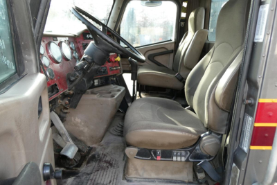 Truck interior showing driver and passenger seats with red dashboard and steering wheel in a 2004 International 9400 daycab.