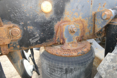 Vehicle hitching area of a 2004 International 9400 showing rusty hitch frame and wheel with visible bolts