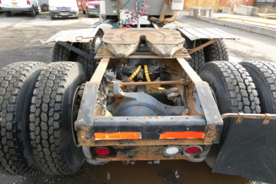 Tractor-trailer rear chassis view of a 2004 International 9400 daycab showing dual rear axles and mud-splattered frame.