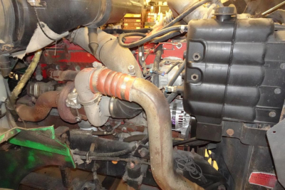 Engine bay of a 2004 International 9400 showing intake manifold, turbo piping, intercooler hoses, and coolant reservoir.