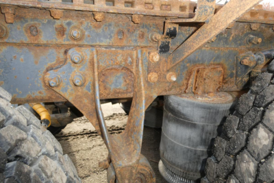 Heavy-duty chassis with rust and wear showing suspension arms and dual tires.