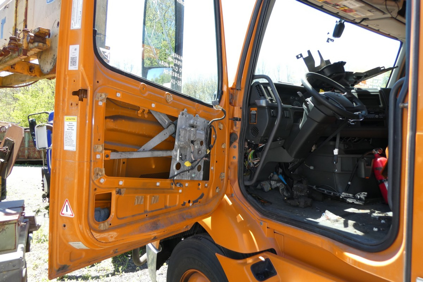 Truck cab interior and open door of a 2019 Volvo VNR truck showing driver seat and dashboard, orange exterior.