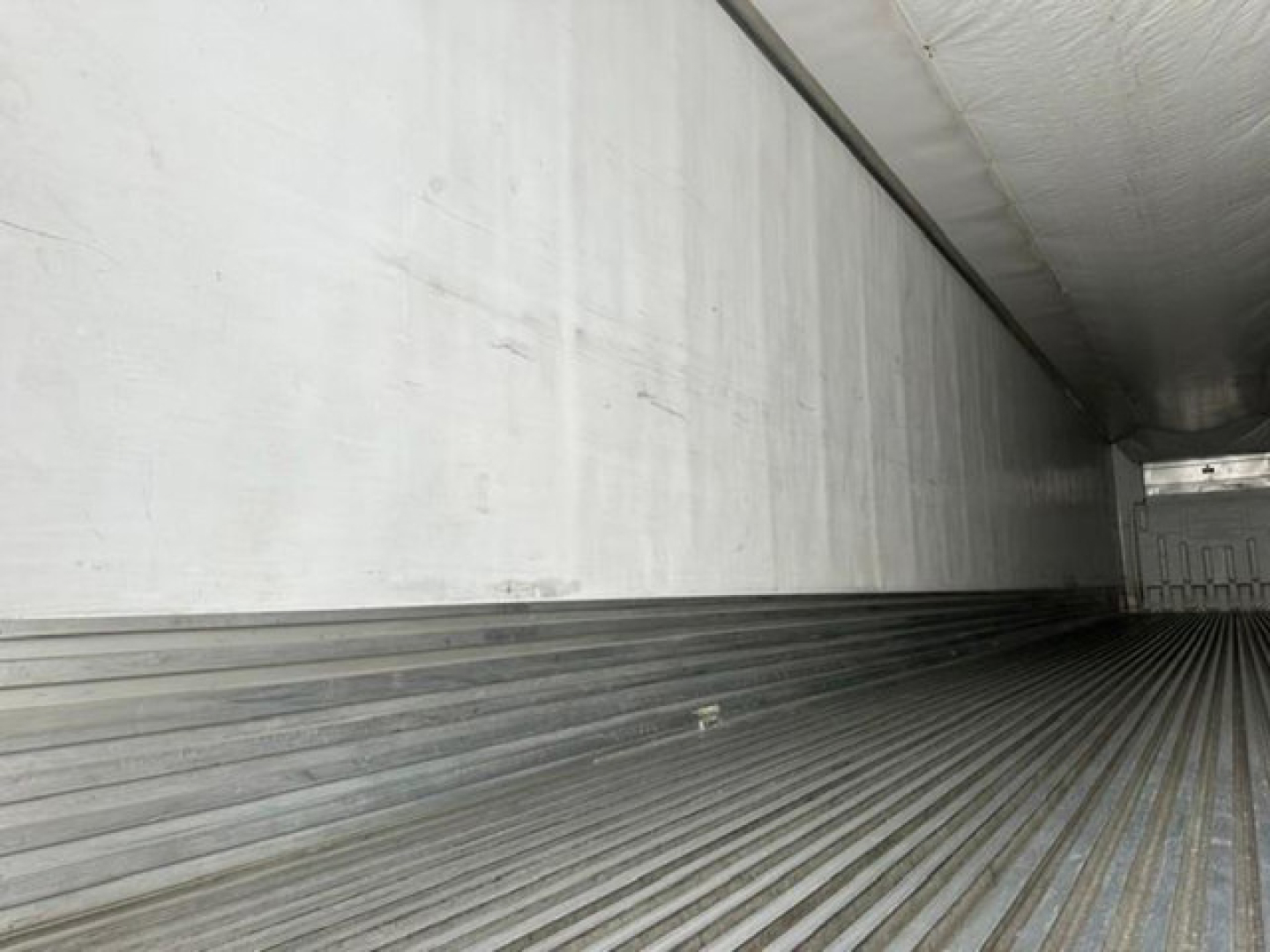 Trailer interior showing ribbed floor and white sidewalls of a refrigerated trailer (referred to as a 2016 Utility Reefer).