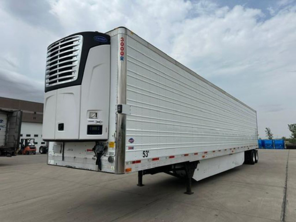 Refrigerated trailer in-service showing roll-up refrigeration unit on the front, white corrugated sides, and landing gear.