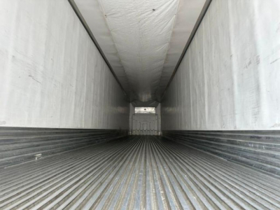 Inside view of a refrigerated trailer cargo area with ribbed floor and insulated walls.