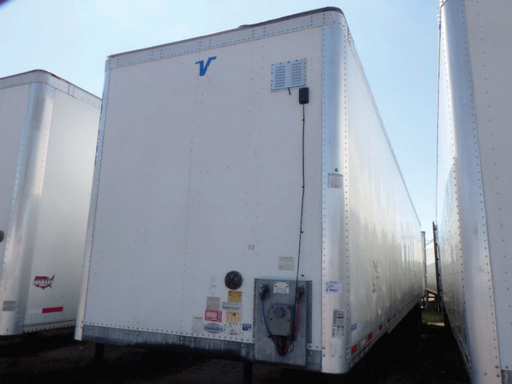 Trailer front view showing a white Vanguard aluminum dry van trailer with a blue Vanguard logo, various stickers near a hitch and a vertical vent panel.