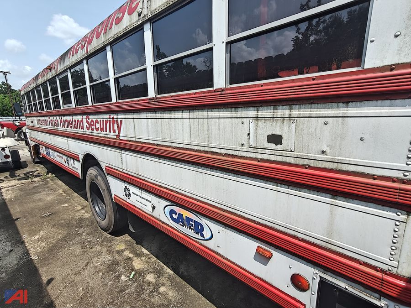 Bus side view showing 1993 Ford B700 bus with metal body, red stripe trim, and CAER logo panel near rear wheel area.