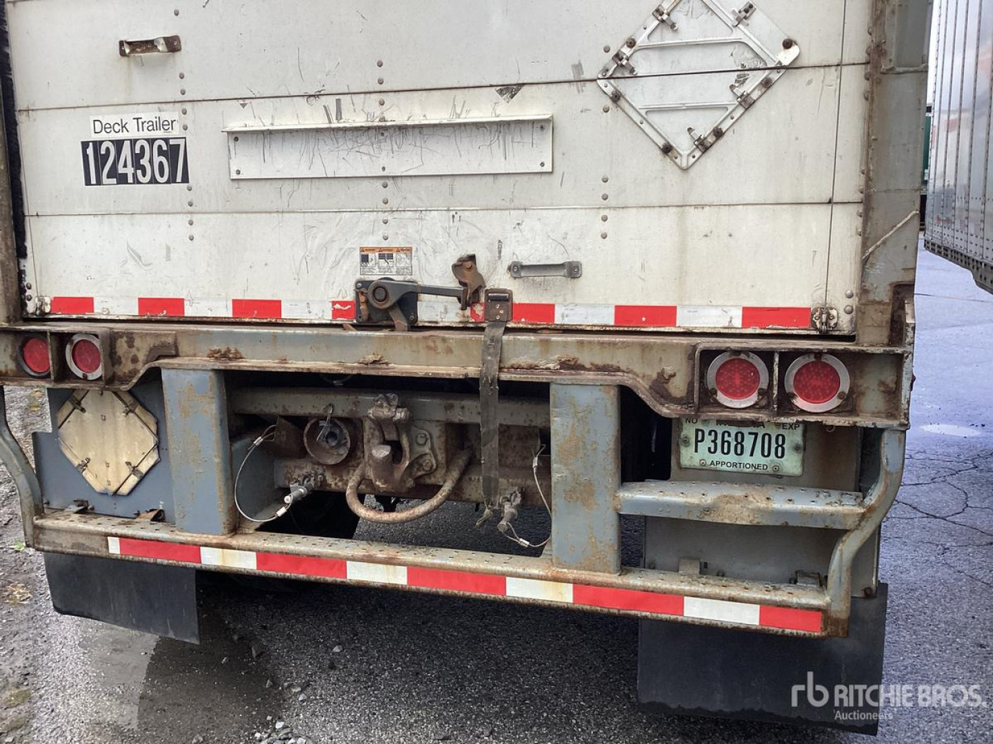 Trailer rear showing bumper, hitch, and rear lights with license plate  P368708 and stock tag 124367. Weathered white trailer with reflective stripes and access doors.