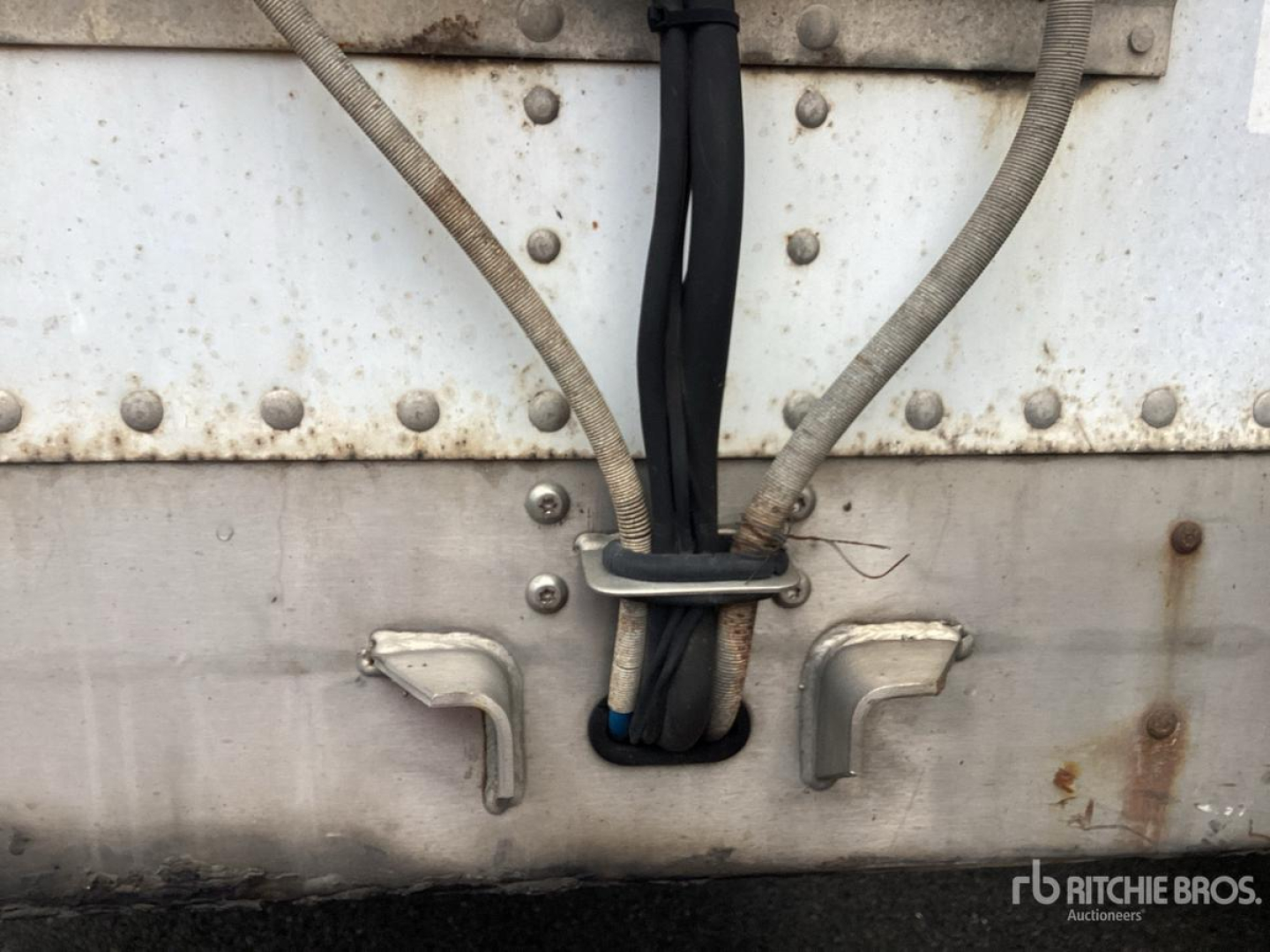 Trailer rear showing electrical cables and weathered metal sides with rivets and latches.