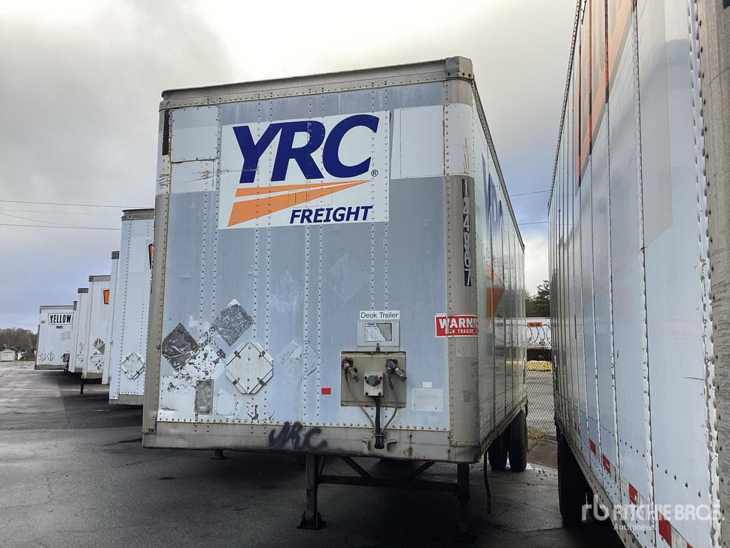 Trailer hitch area of a used Wabash DVDBHPC trailer with YRC Freight logo on the back, surrounded by other trailers in a lot.