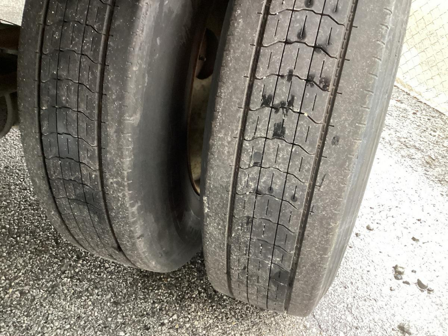 Trailer wheel close-up showing dual tires with tread and wear marks.