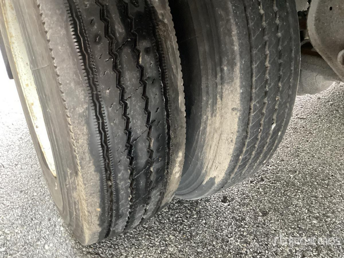 Trailer axle with dual tires showing tread and wear close-up.