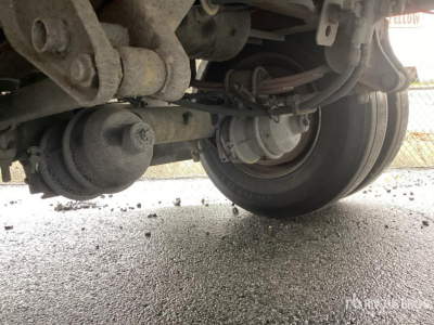 Trailer undercarriage showing axle, suspension, and wheels with visible bolts and hoses.