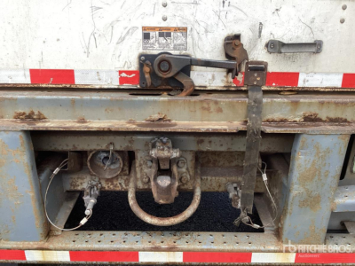 Trailer hitch and frame of a used van trailer showing a circular hitch ring, two side locking mechanisms, and rusted metal with red/white reflective tape.