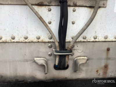Trailer rear showing electrical cables and weathered metal sides with rivets and latches.