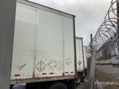 Trailer side of a Wabash DVDBHPC trailer showing a white box body with riveted panels and rear doors, barbed fence in background.