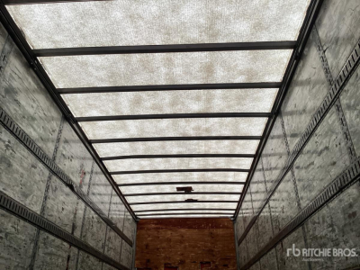 Trailer interior showing aluminum sidewalls with E-Track rails and a wooden raised floor at the far end; translucent roof panels let light in.