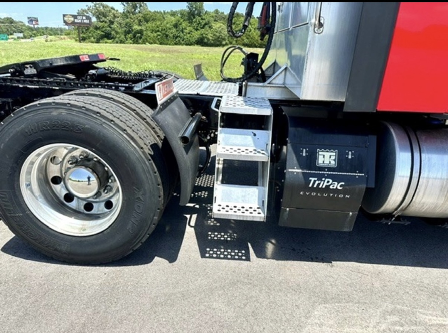 Kenworth T680 2022 cab with TriPac Evolution battery box and metal steps; front wheel and fifth wheel visible; side view shows air cleaner, fuel tanks, and TriPac Evolution unit.
