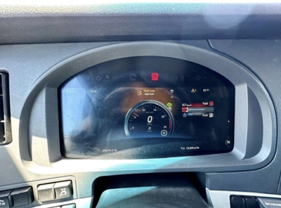 Kenworth truck dashboard display showing digital gauges, fuel level and speedometer in center with various warning icons.