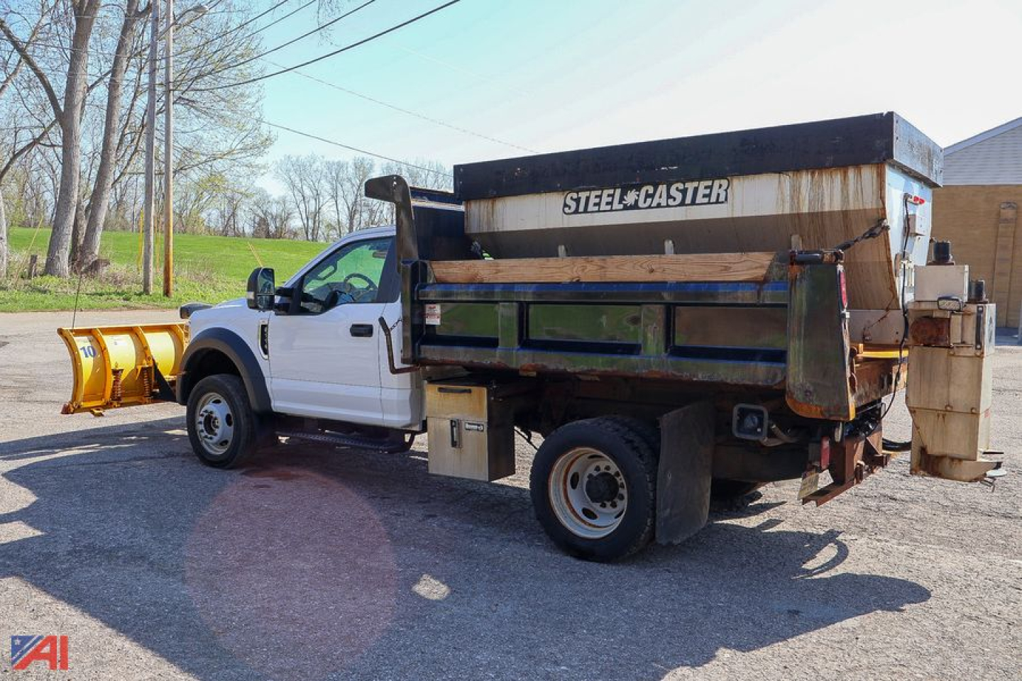 Ford F-550 dump truck with plow and spreader, side view showing steel hopper and rear mounted spreader.