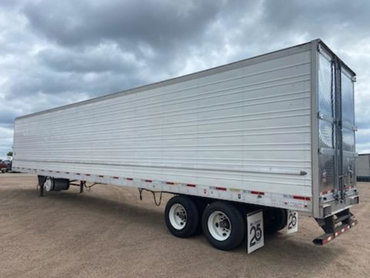 Utility reefer trailer side view showing aluminum exterior, tandem axle, rear doors, and 26 low-profile mudflaps.