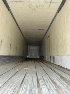 Reefer trailer interior showing long empty cargo space with ribbed metal floor and side walls.