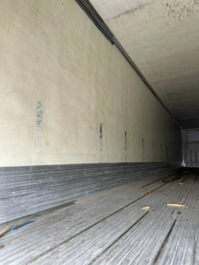 Trailer interior showing empty refrigerated trailer with metal floor and side walls, cargo area in view.