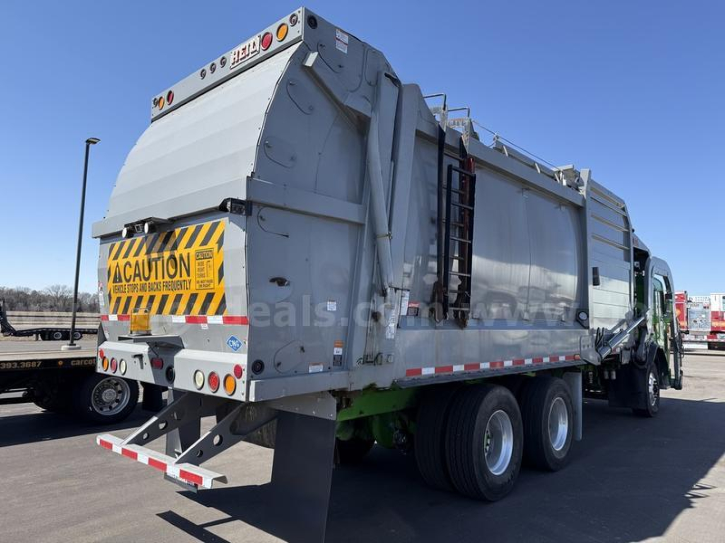 Peterbilt 520 rear and side view garbage truck with a large hopper, safety decals, and dual rear axles.