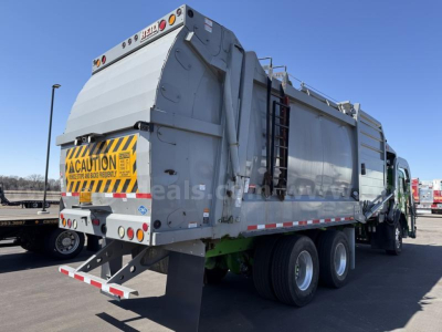 Peterbilt 520 rear and side view garbage truck with a large hopper, safety decals, and dual rear axles.
