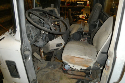 Truck cab interior showing steering wheel, dashboard, and two front seats in a used 1985 Mack R600 daycab.