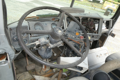 Mack R600 dash and steering wheel with exposed wiring and dashboard components in cabin interior.