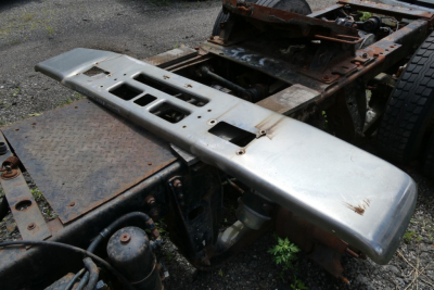 Mack R600 chassis with silver bumper/step and exposed frame, showing metal platform and wheel area in a salvage yard.