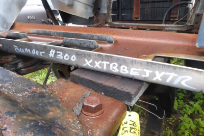 Mack R600 truck frame showing handwritten tag "Bumper #300 XXTBBETXTR" with rust and metal components