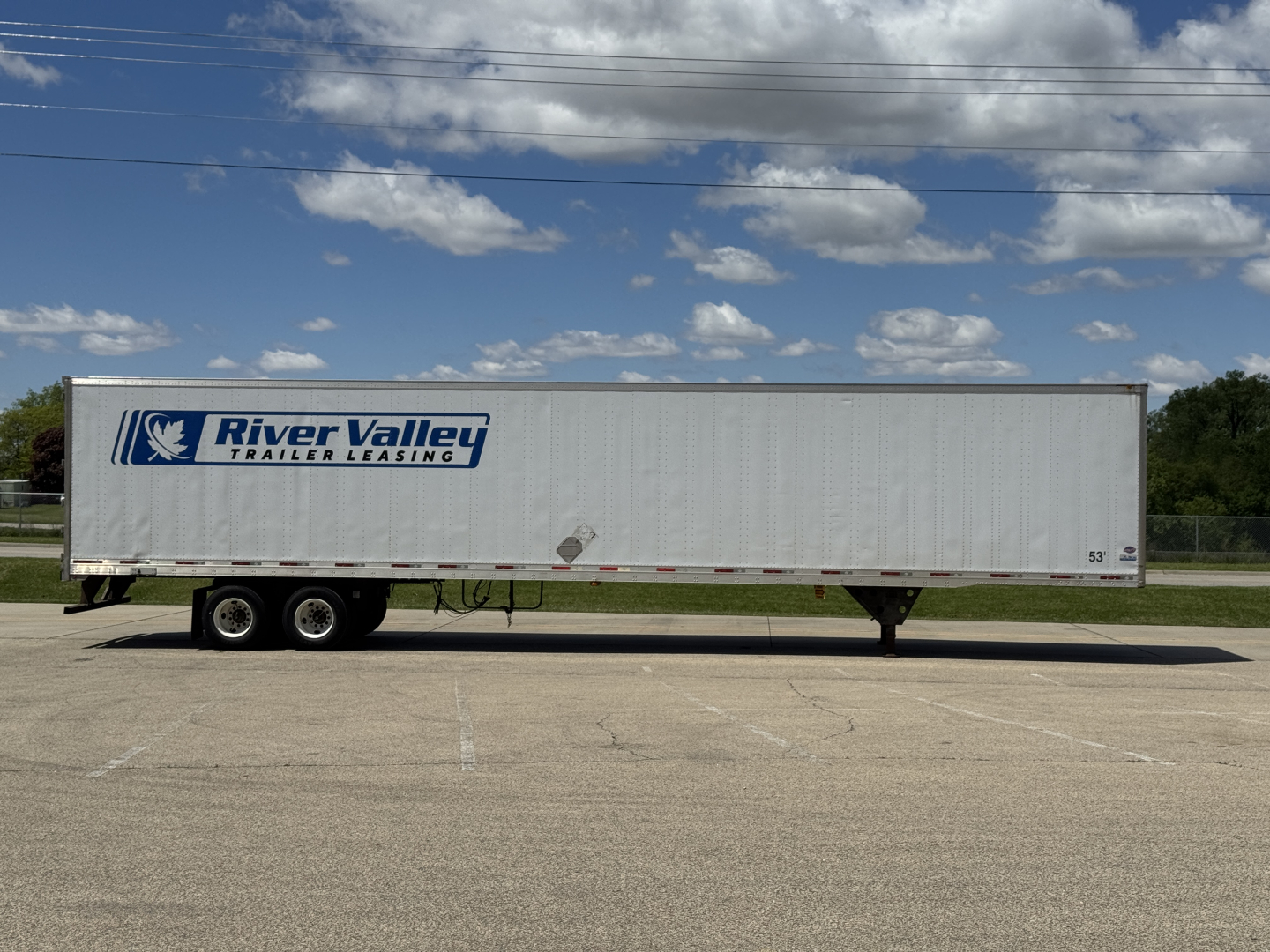 Flat side view of a River Valley Trailers leasing 53' box trailer with logo on white exterior under a blue sky.