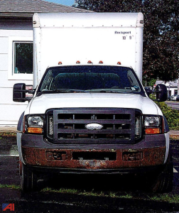 Front view of a white 2006 Ford F-450 Super Duty box truck with a large box behind the cab. The grille is black, headlights are square, and the bumper shows a rust-like texture on the lower area. Roof clearance lights along the top edge of 
