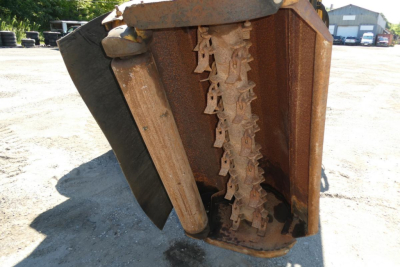 Tractor front loader bucket with cutting teeth and chain mechanism visible in view.