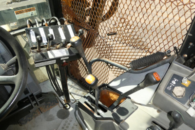 Interior of a Ford 6640 tractor cabin showing control levers and switches with a metal mesh screen in the background.