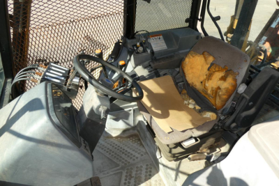 Ford 6640 tractor cab interior showing steering wheel and worn seat with torn upholstery.