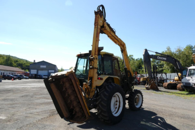 Front-left view of a Ford 6640 tractor with a front loader, hydraulic arm raised, in a lot with other equipment in background.
