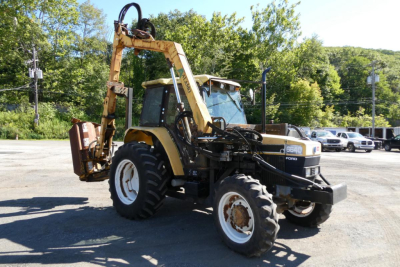 Front three-quarter view of a Ford 6640 tractor with front loader and rear backhoe attachment in a parking lot, showing tires, cab, and hydraulic arms.
